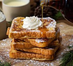 a stack of french toast topped with whipped cream and syrup being drizzled over it