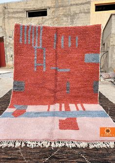 a large red rug on top of a black and white area rug in front of a building