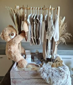 a teddy bear sitting on top of a wooden box next to clothes and other items