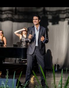 a man standing in front of a piano on stage