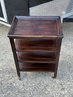 an old wooden table with three shelves on the bottom and one shelf open to reveal something