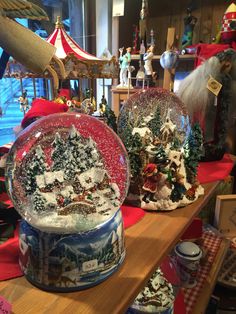 two snow globes sitting on top of a wooden table next to other christmas decorations