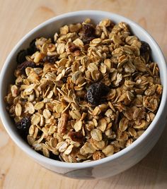 a white bowl filled with granola on top of a wooden table