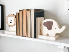 some books are sitting on a shelf next to an elephant and lion figurine