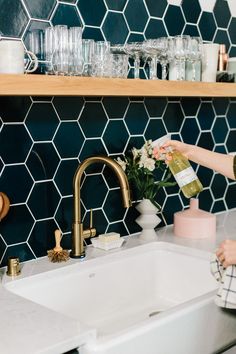 a woman is washing flowers in the kitchen sink while she's cleaning her hands