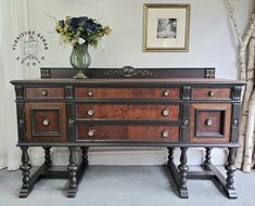 a large wooden dresser sitting next to a vase with flowers on it's top