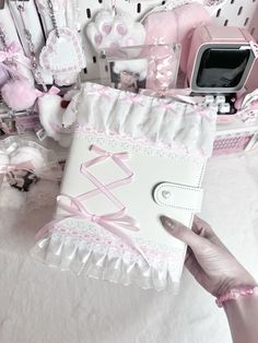 a person holding up a book with pink trimmings and bows on the cover