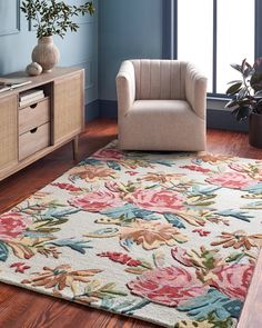 a living room with a chair and rug on the wooden floor next to a window