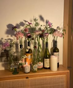 flowers and candles are arranged in vases on a shelf