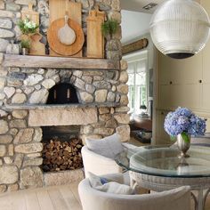 a living room with stone fireplace and glass table