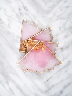 two pieces of pink and gold broochle sitting on top of a marble surface