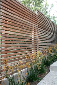 a wooden fence with flowers growing next to it