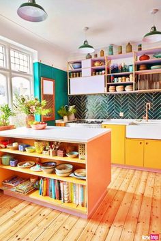 an open kitchen with yellow cabinets and wooden floors is pictured in this image, there are many books on the shelves