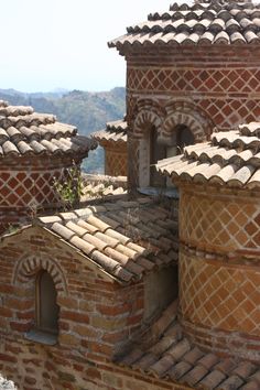 an old building made out of bricks and stone with tiled roof tops in the mountains