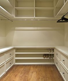 an empty walk in closet with wooden floors and white cabinets, along with wood flooring