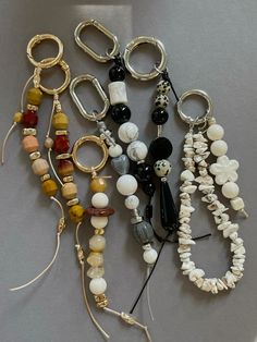 several different types of beaded and metal objects on a gray surface with one being used as a keychain