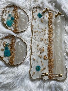 three pieces of glass with gold and blue decorations on them sitting on a white furnishing