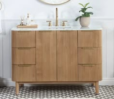 a wooden cabinet with two sinks and a mirror above it in a white walled room