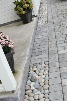 a brick walkway with flowers and potted plants on the side