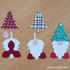 paper cut out christmas trees sitting on top of a wooden table