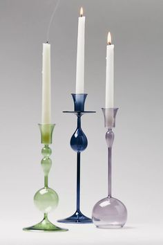 three different colored glass candlesticks sitting next to each other