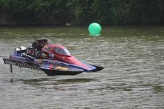 a red and blue jet ski being pulled by a boat in the water next to a green ball