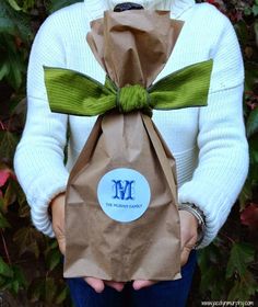 a woman holding a brown paper bag with a green bow