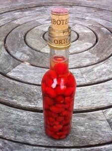 a bottle filled with lots of red liquid sitting on top of a wooden table next to a spiral design