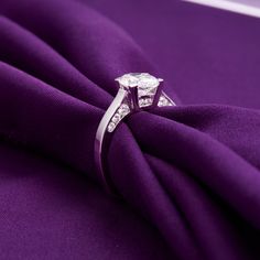 an engagement ring on top of a purple cloth