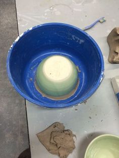 a blue bowl sitting on top of a white table next to other bowls and pottery