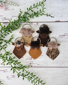 four different animal shaped keychains on top of a white wooden table with greenery