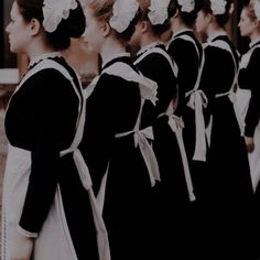 a group of women in black and white dresses standing next to each other with flowers in their hair