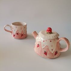 two ceramic teapots with strawberry designs on them