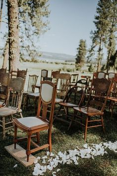 chairs and tables are set up in the grass for an outdoor wedding ceremony with white petals on the ground