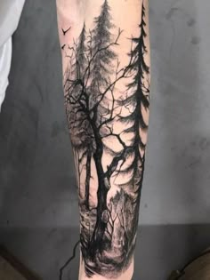 a man's arm with trees and birds in the woods on his left forearm