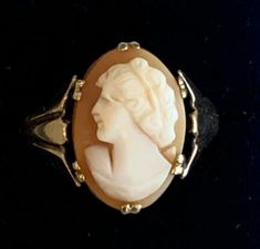 an antique ring with a carved woman's head in the center on a black background