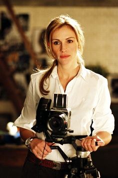 a woman standing next to a camera on top of a tripod