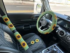 the steering wheel cover is decorated with crochet and has sunflowers on it