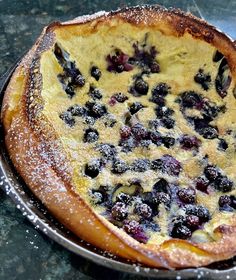 a blueberry pie sitting on top of a metal pan covered in powdered sugar