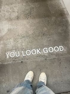 someone is standing on the sidewalk with their feet propped up in front of an inscription that reads, you look good