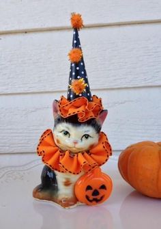 a cat figurine sitting next to a pumpkin