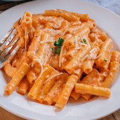 a white plate topped with pasta covered in sauce and parmesan cheese next to a fork