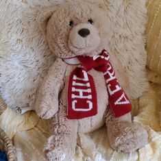 a teddy bear with a red scarf on it's neck sitting in a chair