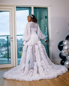 a woman in a white dress is standing on a wooden floor with balloons behind her