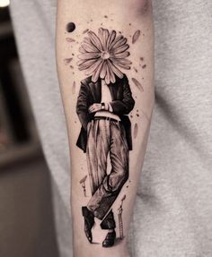 a man's arm with a flower and a clown tattoo on the left forearm