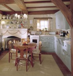 an old fashioned kitchen with white appliances and wood beams on the ceiling, along with a fireplace