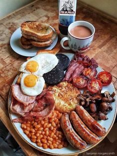 a breakfast plate with eggs, sausages, beans, toast and bacon on it