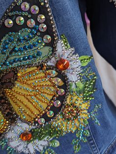 the back of a woman's jean jacket with sequins and beads