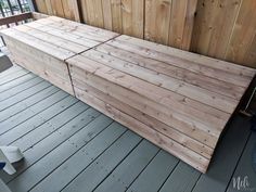 a large wooden bench sitting on top of a porch next to a wall with wood slats