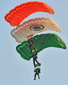 two people are parasailing in the sky with their parachutes attached to them